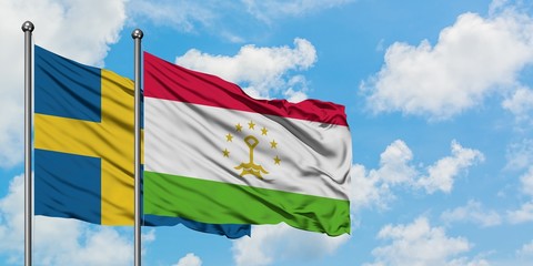 Sweden and Tajikistan flag waving in the wind against white cloudy blue sky together. Diplomacy concept, international relations.