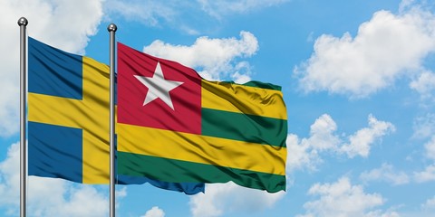 Sweden and Togo flag waving in the wind against white cloudy blue sky together. Diplomacy concept, international relations.
