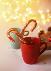 Obraz na płótnie Canvas Blue and red mugs with christmas candies. Blurred lights shiny bokeh backgound.