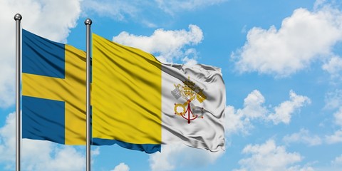 Sweden and Vatican City flag waving in the wind against white cloudy blue sky together. Diplomacy concept, international relations.