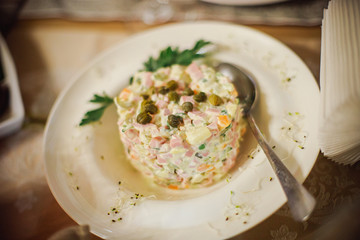 salad on white plate in restaurant. Iron spoon in plate with cold appetizer. Microgreen for decorating dishes in cafe. Traditional Russian Christmas and New year salad 