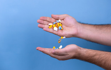A pile of multi-colored pills in a male hand. A man holds pills in his hand. The concept of medicine, illness, health