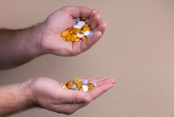A pile of multi-colored pills in a male hand. A man holds pills in his hand. The concept of medicine, illness, health