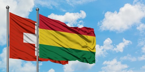 Switzerland and Bolivia flag waving in the wind against white cloudy blue sky together. Diplomacy concept, international relations.