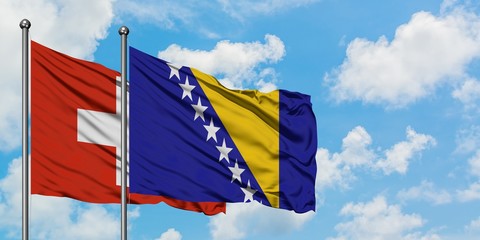 Switzerland and Bosnia Herzegovina flag waving in the wind against white cloudy blue sky together. Diplomacy concept, international relations.