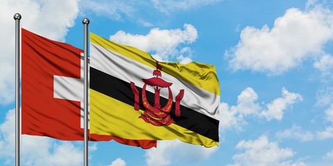 Switzerland and Brunei flag waving in the wind against white cloudy blue sky together. Diplomacy concept, international relations.