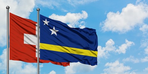 Switzerland and Curacao flag waving in the wind against white cloudy blue sky together. Diplomacy concept, international relations.