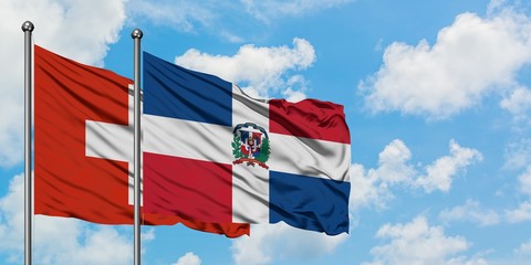 Switzerland and Dominican Republic flag waving in the wind against white cloudy blue sky together. Diplomacy concept, international relations.