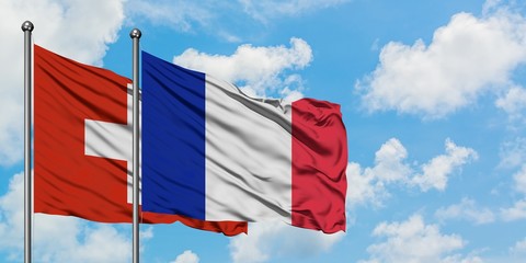 Switzerland and France flag waving in the wind against white cloudy blue sky together. Diplomacy concept, international relations.