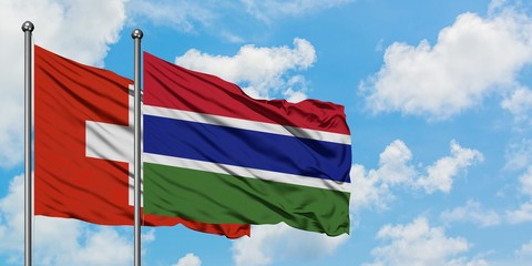 Switzerland and Gambia flag waving in the wind against white cloudy blue sky together. Diplomacy concept, international relations.