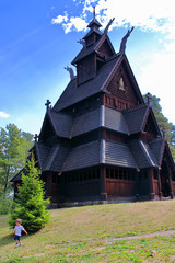 Little two years old boy running and playing in front of the Gol Church,  a stave church originally...