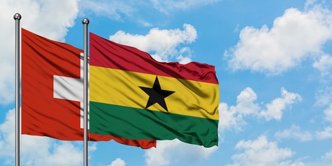 Switzerland and Ghana flag waving in the wind against white cloudy blue sky together. Diplomacy concept, international relations.