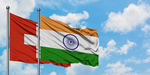 Switzerland and India flag waving in the wind against white cloudy blue sky together. Diplomacy...