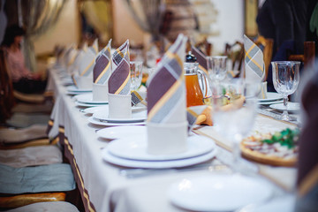 Beautifully folded napkins on a served table. Brown napkins on a white plate. Celebration in the restaurant. Cafe party at the banquet.