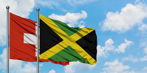 Switzerland and Jamaica flag waving in the wind against white cloudy blue sky together. Diplomacy concept, international relations.