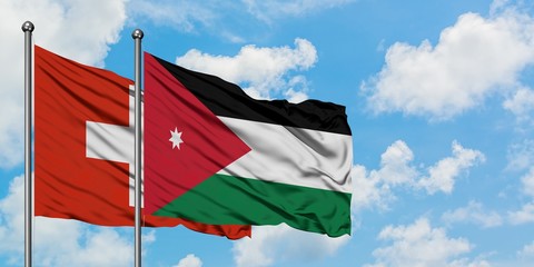 Switzerland and Jordan flag waving in the wind against white cloudy blue sky together. Diplomacy concept, international relations.
