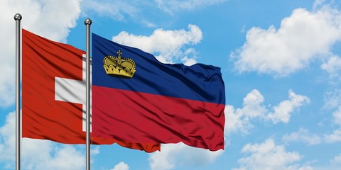 Switzerland and Liechtenstein flag waving in the wind against white cloudy blue sky together. Diplomacy concept, international relations.