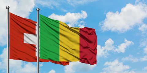 Switzerland and Mali flag waving in the wind against white cloudy blue sky together. Diplomacy concept, international relations.