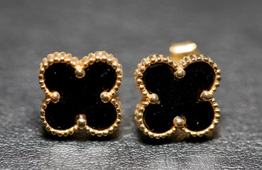 Small black clover earrings on white background. - Image