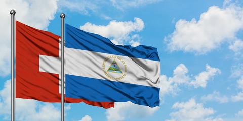 Switzerland and Nicaragua flag waving in the wind against white cloudy blue sky together. Diplomacy concept, international relations.
