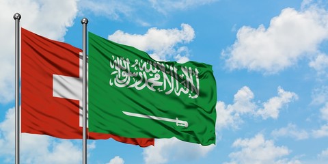 Switzerland and Saudi Arabia flag waving in the wind against white cloudy blue sky together. Diplomacy concept, international relations.