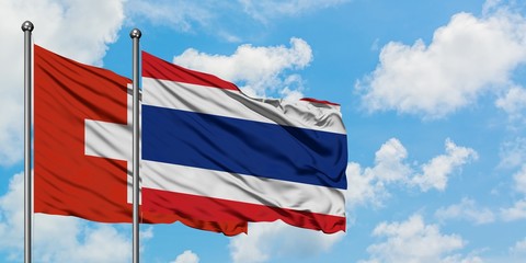 Switzerland and Thailand flag waving in the wind against white cloudy blue sky together. Diplomacy concept, international relations.