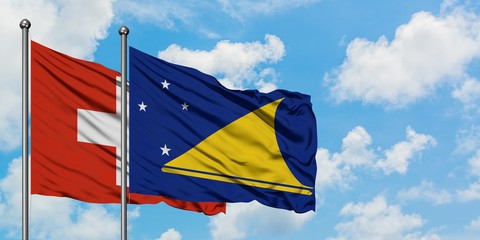 Switzerland and Tokelau flag waving in the wind against white cloudy blue sky together. Diplomacy concept, international relations.