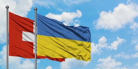 Switzerland and Ukraine flag waving in the wind against white cloudy blue sky together. Diplomacy concept, international relations.