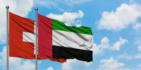 Switzerland and United Arab Emirates flag waving in the wind against white cloudy blue sky together. Diplomacy concept, international relations.