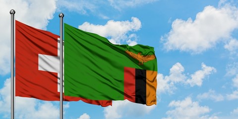 Switzerland and Zambia flag waving in the wind against white cloudy blue sky together. Diplomacy concept, international relations.