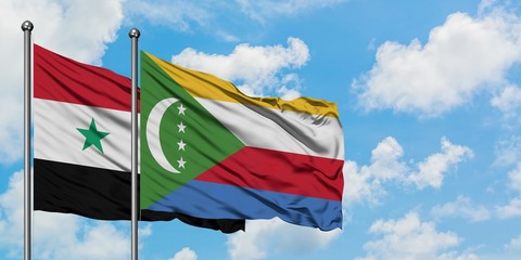 Syria and Comoros flag waving in the wind against white cloudy blue sky together. Diplomacy concept, international relations.