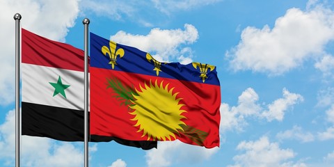 Syria and Guadeloupe flag waving in the wind against white cloudy blue sky together. Diplomacy...