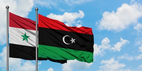 Syria and Libya flag waving in the wind against white cloudy blue sky together. Diplomacy concept, international relations.