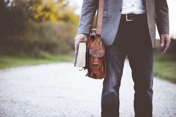 Closeup shot of a male with a bag and holding the bible with a blurred background
