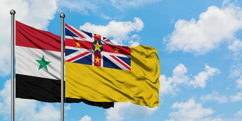 Syria and Niue flag waving in the wind against white cloudy blue sky together. Diplomacy concept, international relations.