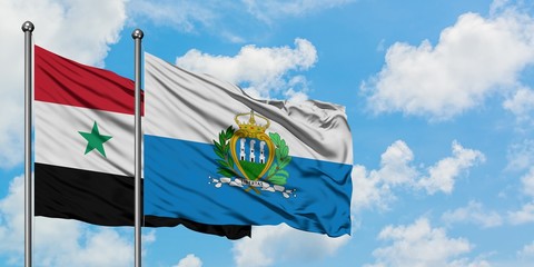 Syria and San Marino flag waving in the wind against white cloudy blue sky together. Diplomacy...