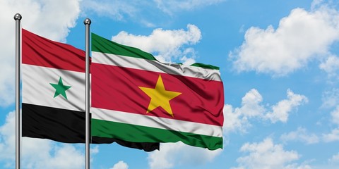 Syria and Suriname flag waving in the wind against white cloudy blue sky together. Diplomacy concept, international relations.