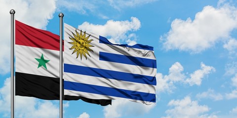 Syria and Uruguay flag waving in the wind against white cloudy blue sky together. Diplomacy...
