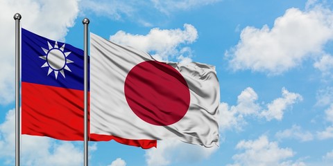 Taiwan and Japan flag waving in the wind against white cloudy blue sky together. Diplomacy concept, international relations.