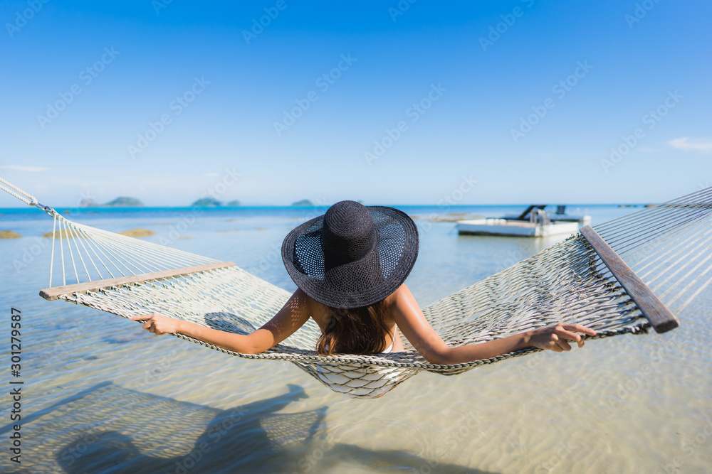 Wall mural portrait beautiful young asian woman sitting on hammock around sea beach ocean for relax