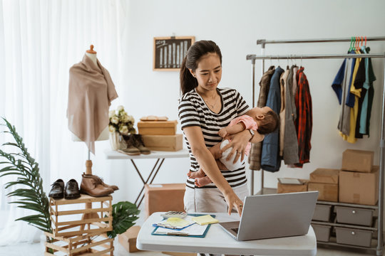 portrait of woman with baby working from home of her online ecommerce shop