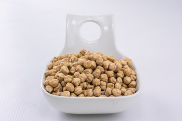 Front view of a bowl with raw chickpeas for cooking on white background