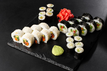 Various kinds of sushi served on black background. Sushi menu for Japanese food. Japanese sushi set. Vegan rolls and maki with carrot, cucumber, tomato and avocado. Horizontal photo