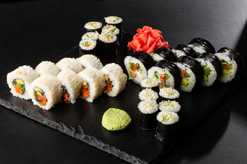 Various kinds of sushi served on black background. Sushi menu for Japanese food. Japanese sushi set. Vegan rolls and maki with carrot, cucumber, tomato and avocado. Horizontal photo