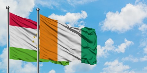 Tajikistan and Cote D'Ivoire flag waving in the wind against white cloudy blue sky together. Diplomacy concept, international relations.