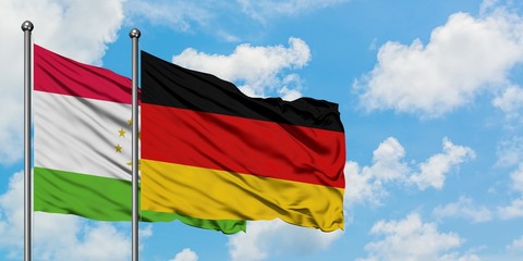 Tajikistan and Germany flag waving in the wind against white cloudy blue sky together. Diplomacy concept, international relations.