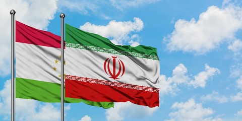 Tajikistan and Iran flag waving in the wind against white cloudy blue sky together. Diplomacy concept, international relations.
