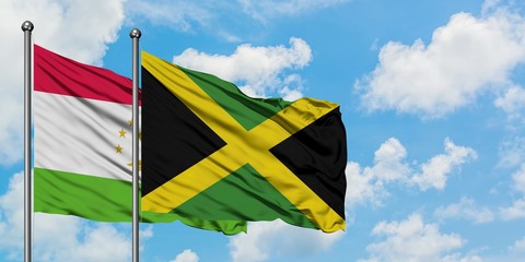 Tajikistan and Jamaica flag waving in the wind against white cloudy blue sky together. Diplomacy concept, international relations.