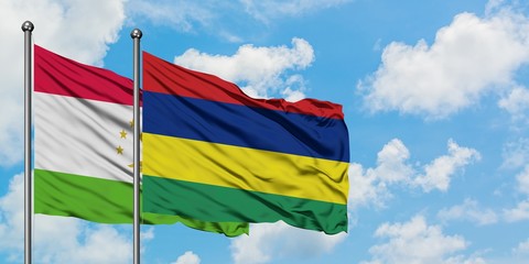 Tajikistan and Mauritius flag waving in the wind against white cloudy blue sky together. Diplomacy concept, international relations.