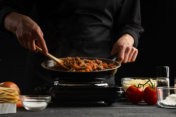 Chef fry vegetables with meat for cooking a delicious dish. On a black background